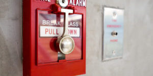 Push button switch fire alarm on mortar wall for alarm and security system with fire extinguisher port.